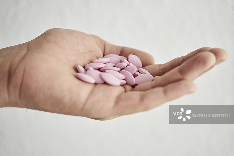手持粉色药丸（白色背景）图片素材