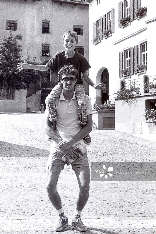 年轻的父亲和儿子在他的肩膀上保持平衡图片素材