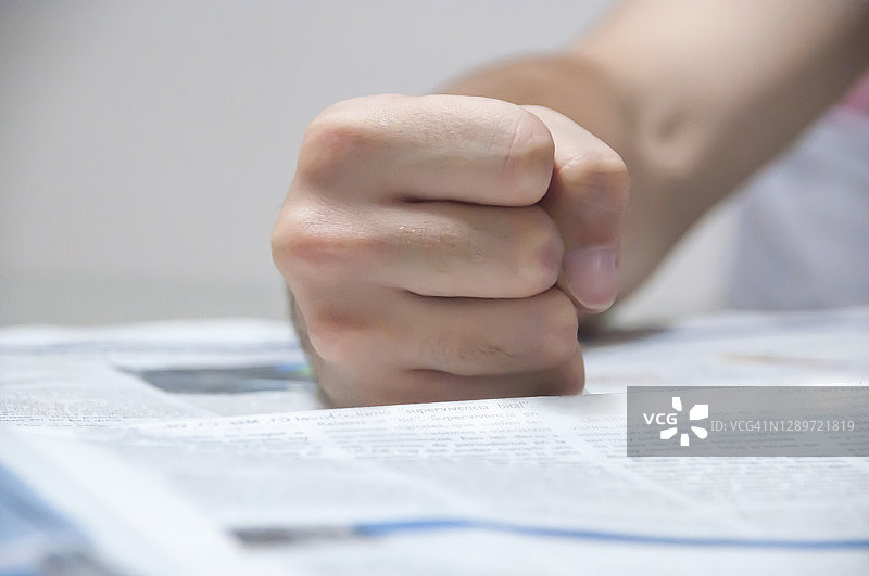 愤怒的男人在报纸上的拳头特写图片素材