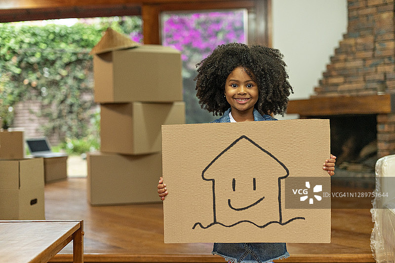 拿着新房图画海报的棕色皮肤非洲发型拉丁裔女孩图片素材
