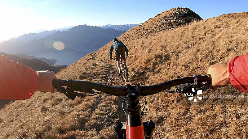 山地自行车手从高山草甸下降的车把视角图片素材