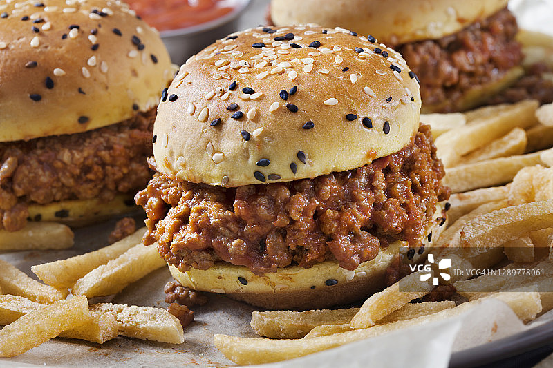 放在奶油芝麻面包上的凌乱的乔滑块和炸薯条图片素材