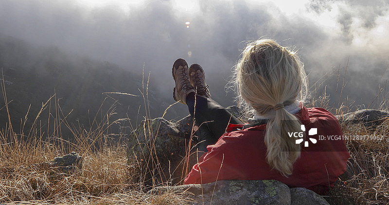 中年妇女在高山草甸上放松，观看远山雾气消散图片素材