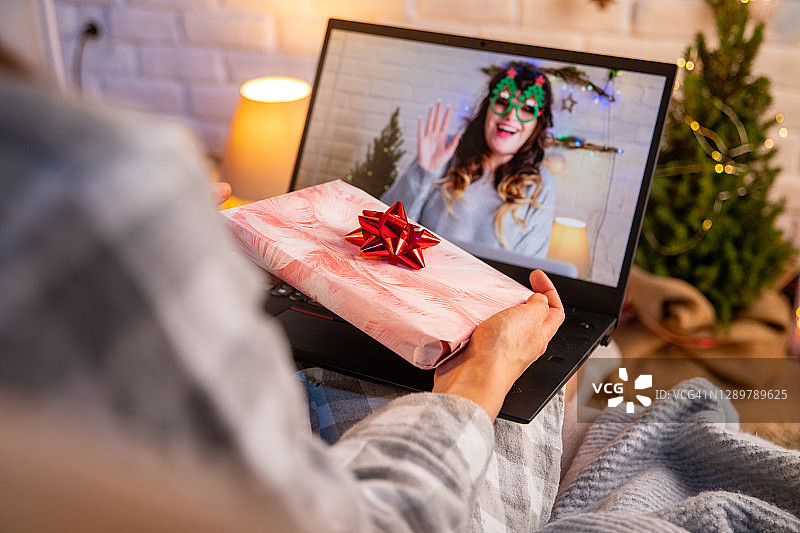 穿着红色睡衣的女孩在电脑视频通话中向朋友展示圣诞礼物图片素材