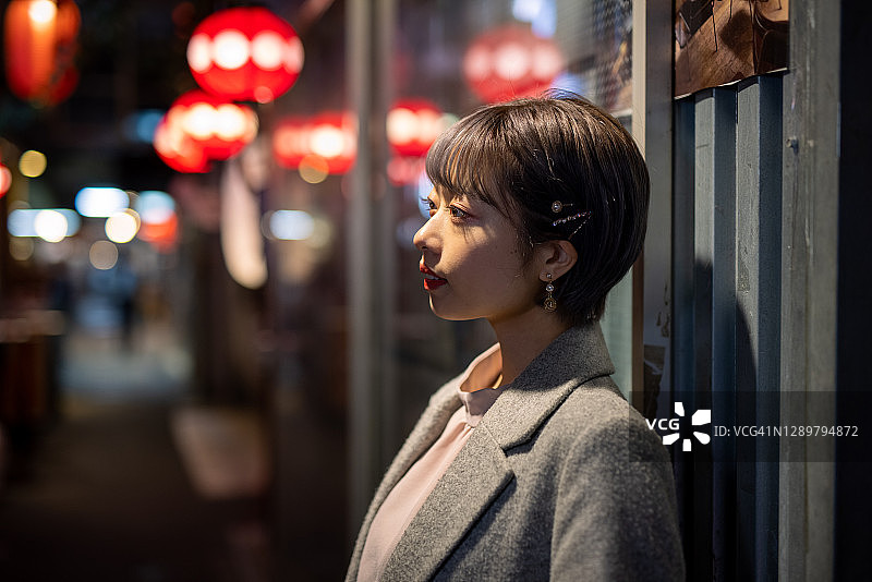 在日本居酒屋酒吧街靠墙的年轻女人图片素材