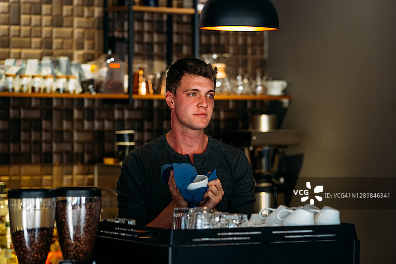 咖啡店里用毛巾擦拭杯子的咖啡师图片素材