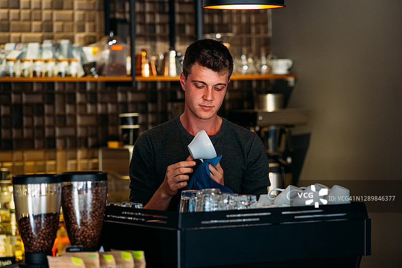 咖啡店里用毛巾擦拭杯子的咖啡师图片素材