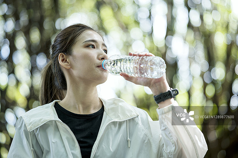 户外锻炼后喝水的疲惫亚洲年轻女性图片素材