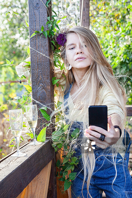 在露台上自拍的戴着鲜花的年轻女子图片素材