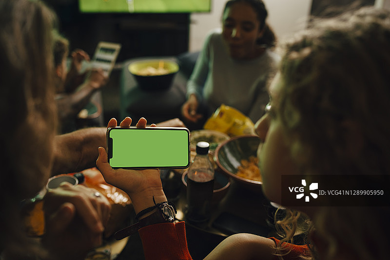 女儿和母亲在体育赛事期间观看智能手机的后视图图片素材