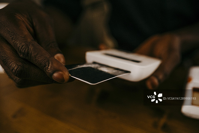 咖啡店主在厨房柜台上使用信用卡读卡器的特写图片素材