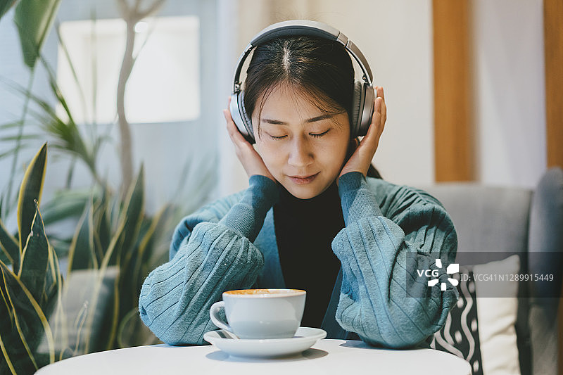 一边喝咖啡一边听音乐的亚洲女孩图片素材