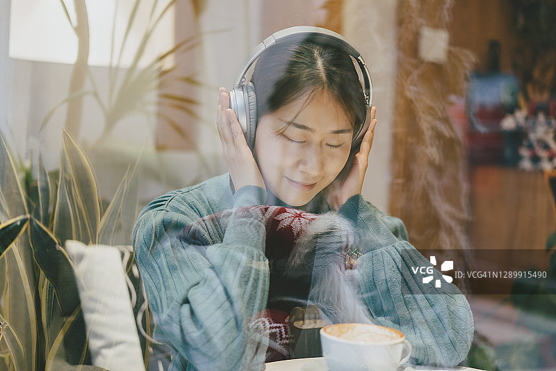 一边喝咖啡一边听音乐的亚洲女孩图片素材