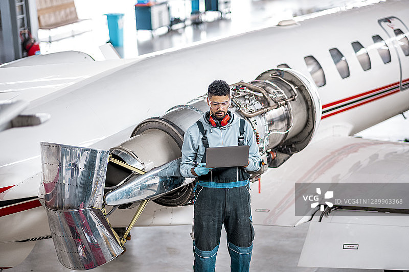 飞机机械师使用笔记本电脑检查飞机喷气发动机图片素材