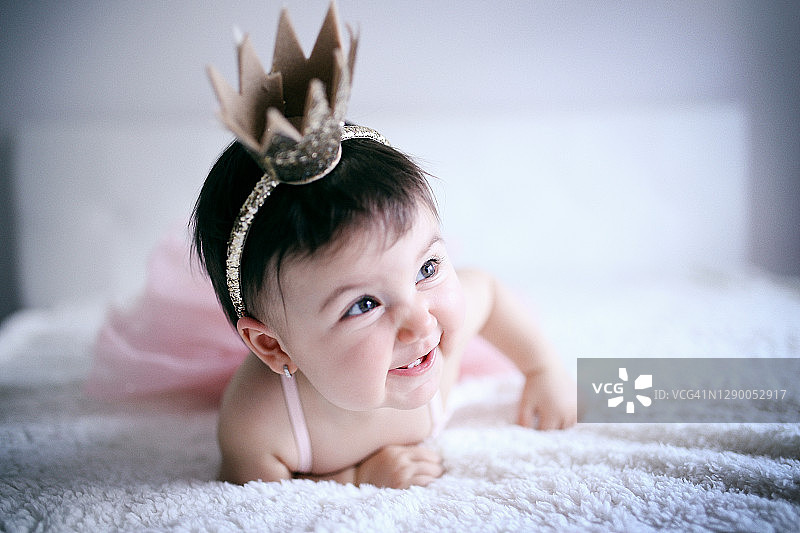 穿着粉色芭蕾舞裙和金色皇冠的可爱宝宝爬行居家照图片素材