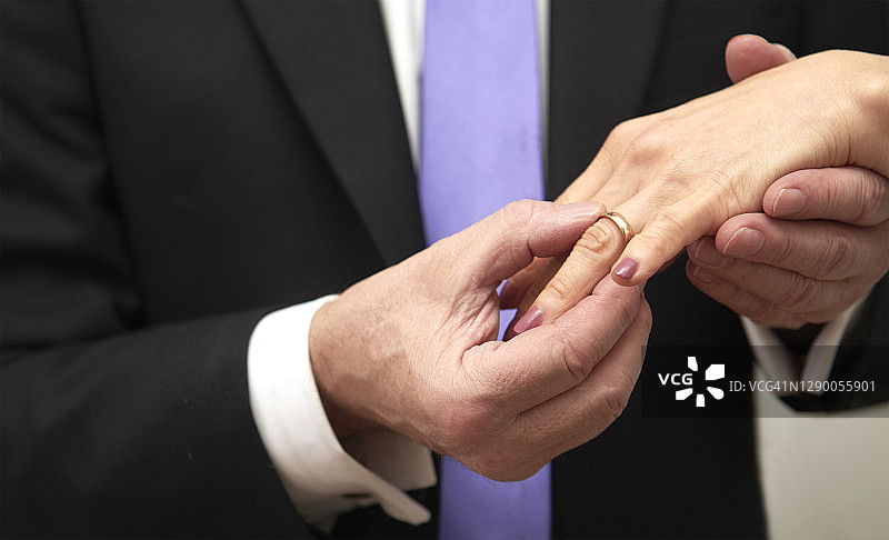 新郎将结婚戒指戴在新娘的手指上图片素材