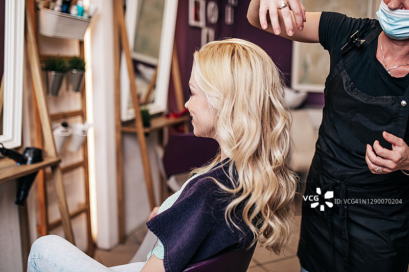 在美发沙龙接受护理的戴防护面罩的女人图片素材