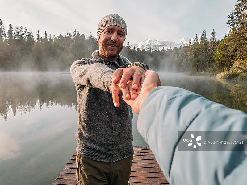 男人在日出时带领女友走向木制码头图片素材