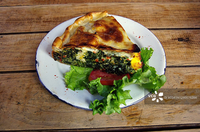木桌上盘子里的帕斯夸利纳（菠菜鸡蛋派）切片图片素材