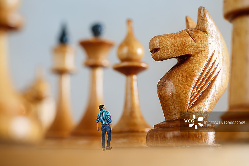 站在棋盘上仰望巨大棋子的小人图片素材