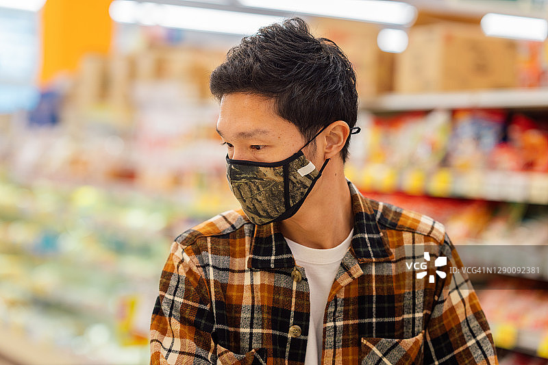 戴防护口罩的年轻男人在超市购物图片素材