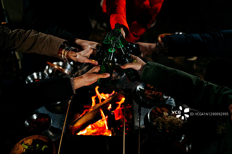 一群朋友坐在篝火旁，在冬天享受美食和饮料图片素材