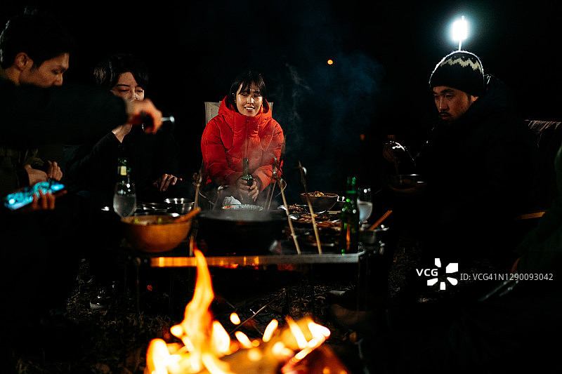 一群朋友坐在篝火旁，在冬天享受美食和饮料图片素材