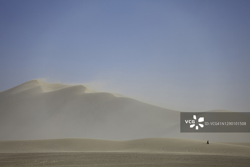 在加利福尼亚州迪蒙沙丘的沙尘暴中坐在沙丘上的人图片素材