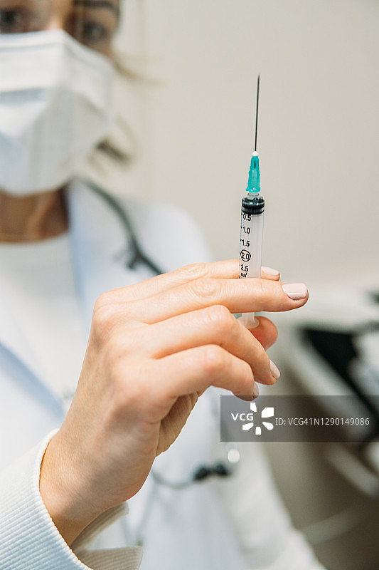 医生手持注射器填充冠状病毒疫苗图片素材