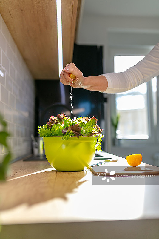 手将柠檬汁挤在碗里的生菜上图片素材