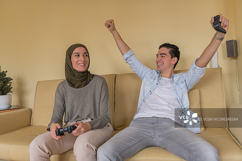 在家一起玩游戏机的英俊青年和中东裔女友图片素材