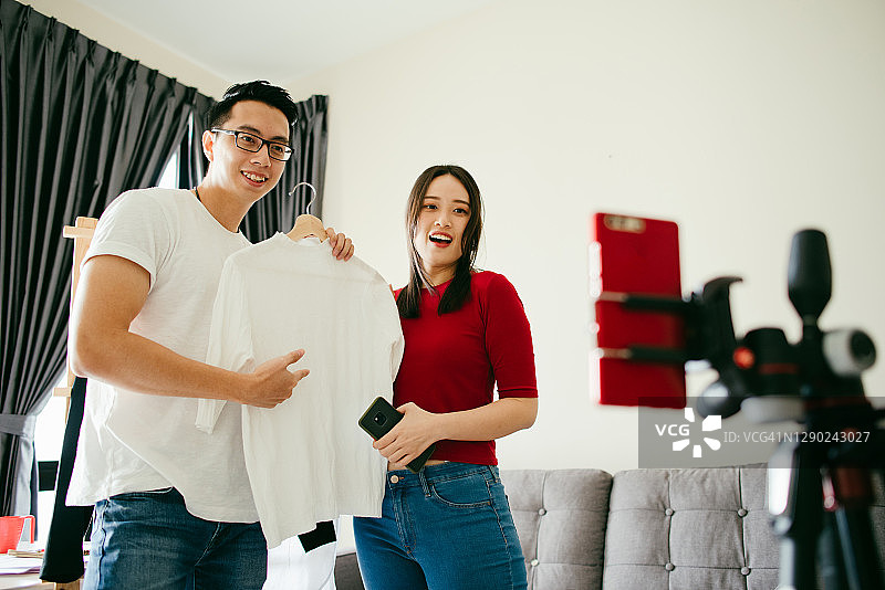 亚洲年轻博主在直播中评论产品，在家工作图片素材