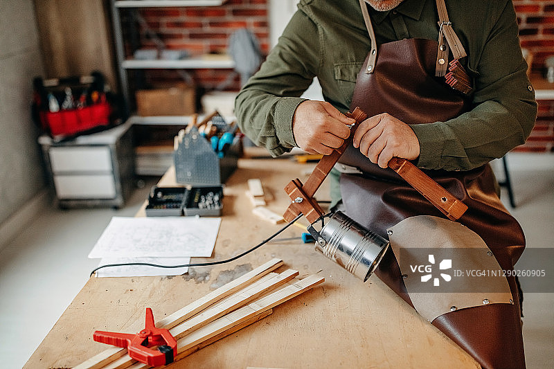 男子在小型家庭木工工厂组装木制灯图片素材