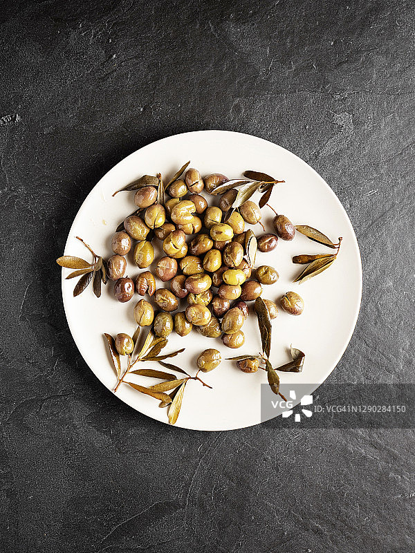 腌制绿色橄榄和橄榄树枝的扁平图，橄榄被压碎图片素材