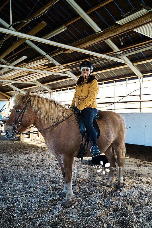 快乐女骑师坐在马厩的马背上图片素材