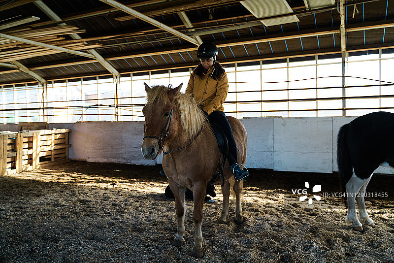 快乐女骑师坐在马厩的马背上图片素材