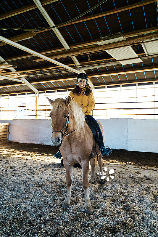 快乐女骑师坐在马厩的马背上图片素材