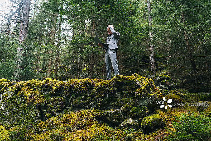 商务男士在茂密的森林中远程办公图片素材
