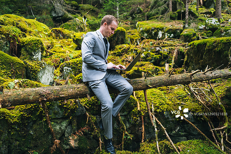 商务男士在茂密的森林中远程办公图片素材