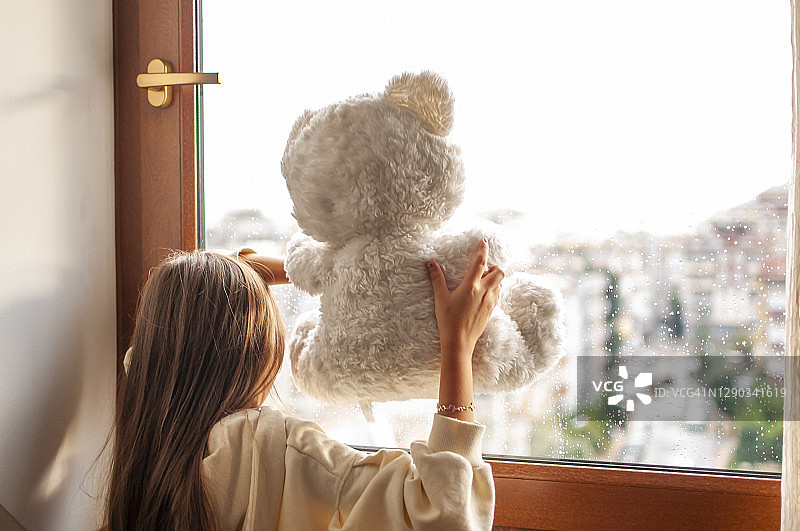 在家和泰迪熊一起感到无聊的可爱女孩图片素材