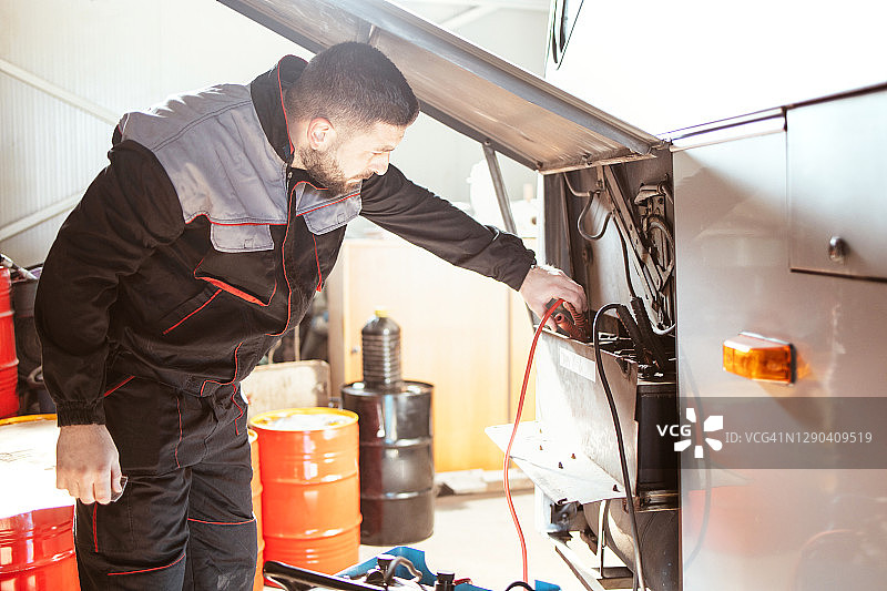 男人用充电器为公交车电池充电图片素材