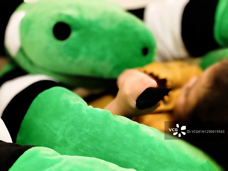 混血女童抱着毛绒玩具蛇的舌头睡觉图片素材