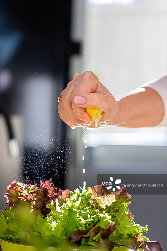 手挤柠檬汁，溅在罗莎红生菜上图片素材