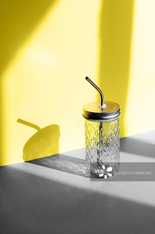 灰色金色背景上带有可重复使用金属吸管的饮料玻璃瓶图片素材
