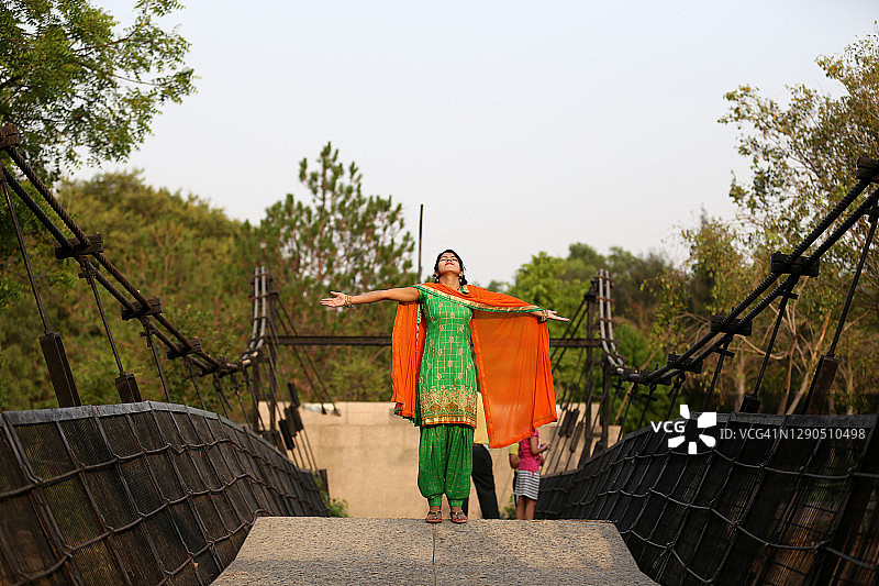 年轻女子站在桥上，举起双臂呼吸新鲜空气图片素材