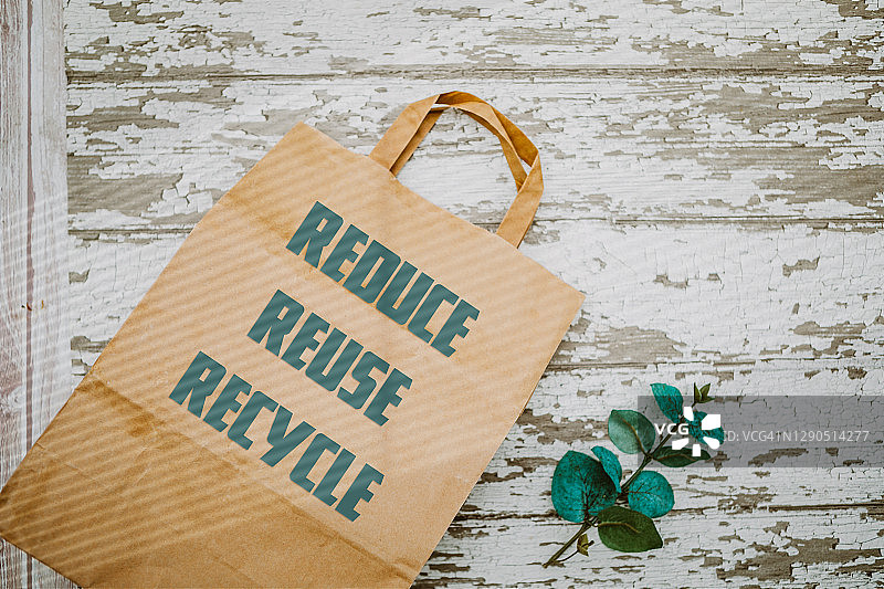 绿色背景上的再生纸袋，写着重复使用、减少和回收图片素材