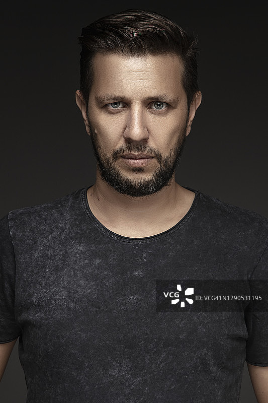 黑色背景下眼睛色彩鲜艳的英俊年轻男子影棚照图片素材