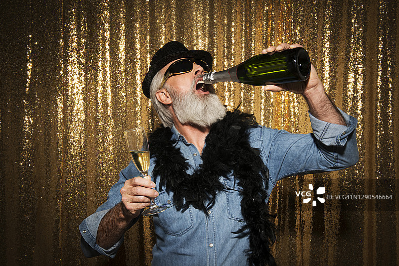 在照相亭里戴着有趣道具拍照的年长男人图片素材