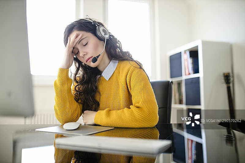 疲惫的女心理医生佩戴耳机看着镜头，远程在线医疗聊天咨询，远程医疗服务，虚拟医生电话会议概念图片素材