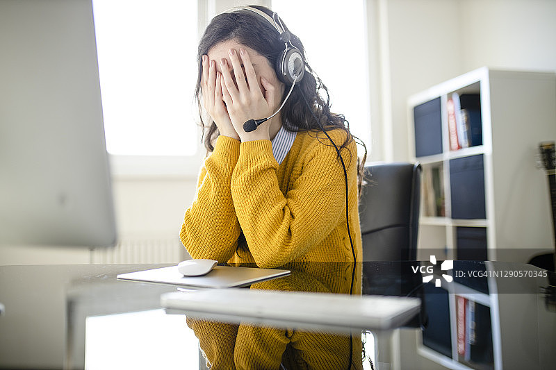 疲惫的女心理医生佩戴耳机看着镜头，远程在线医疗聊天咨询，远程医疗服务，虚拟医生电话会议概念图片素材
